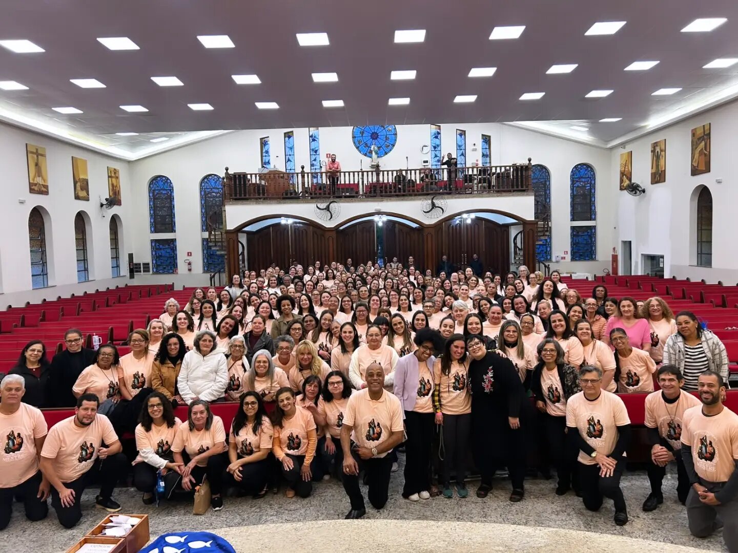 Participantes do 1º Retiro de Mulheres, de camisetas cor de pêssego, na igreja